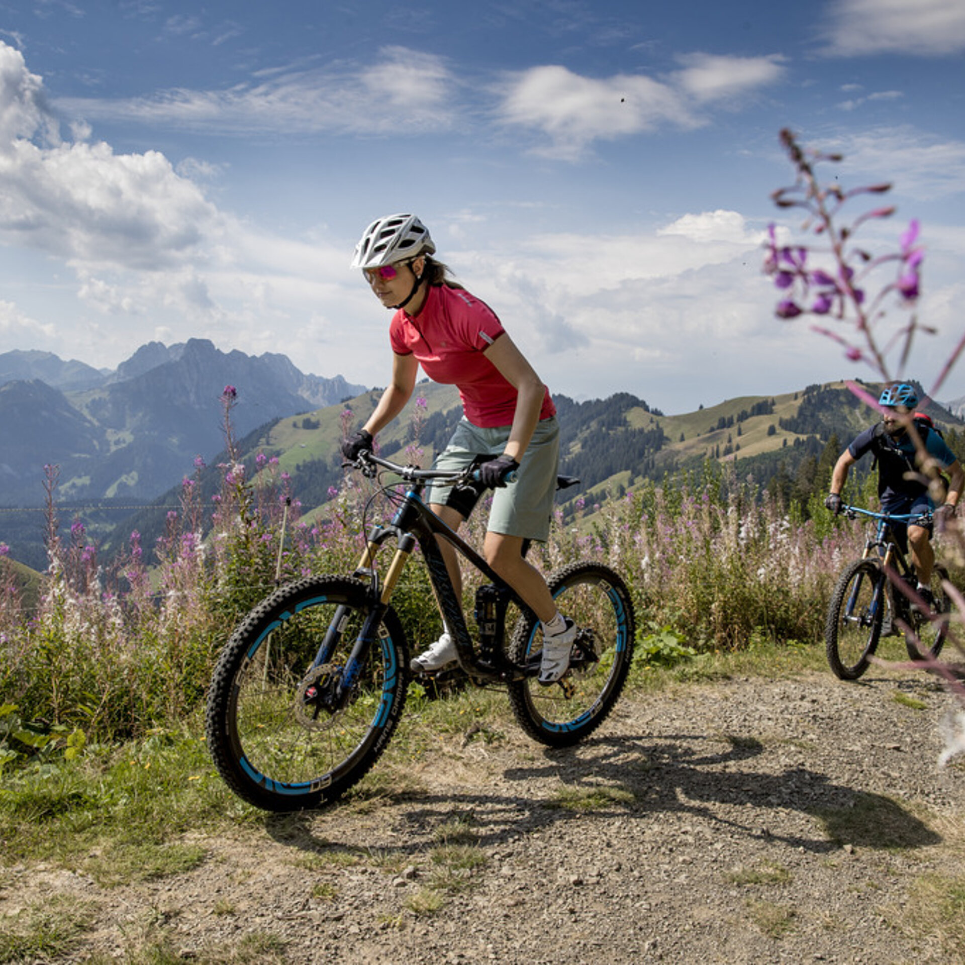 Tochter mit Vater auf der Rellerli Bike Route auf breitem Singletrail. Weidenröschen säumen den Weg.