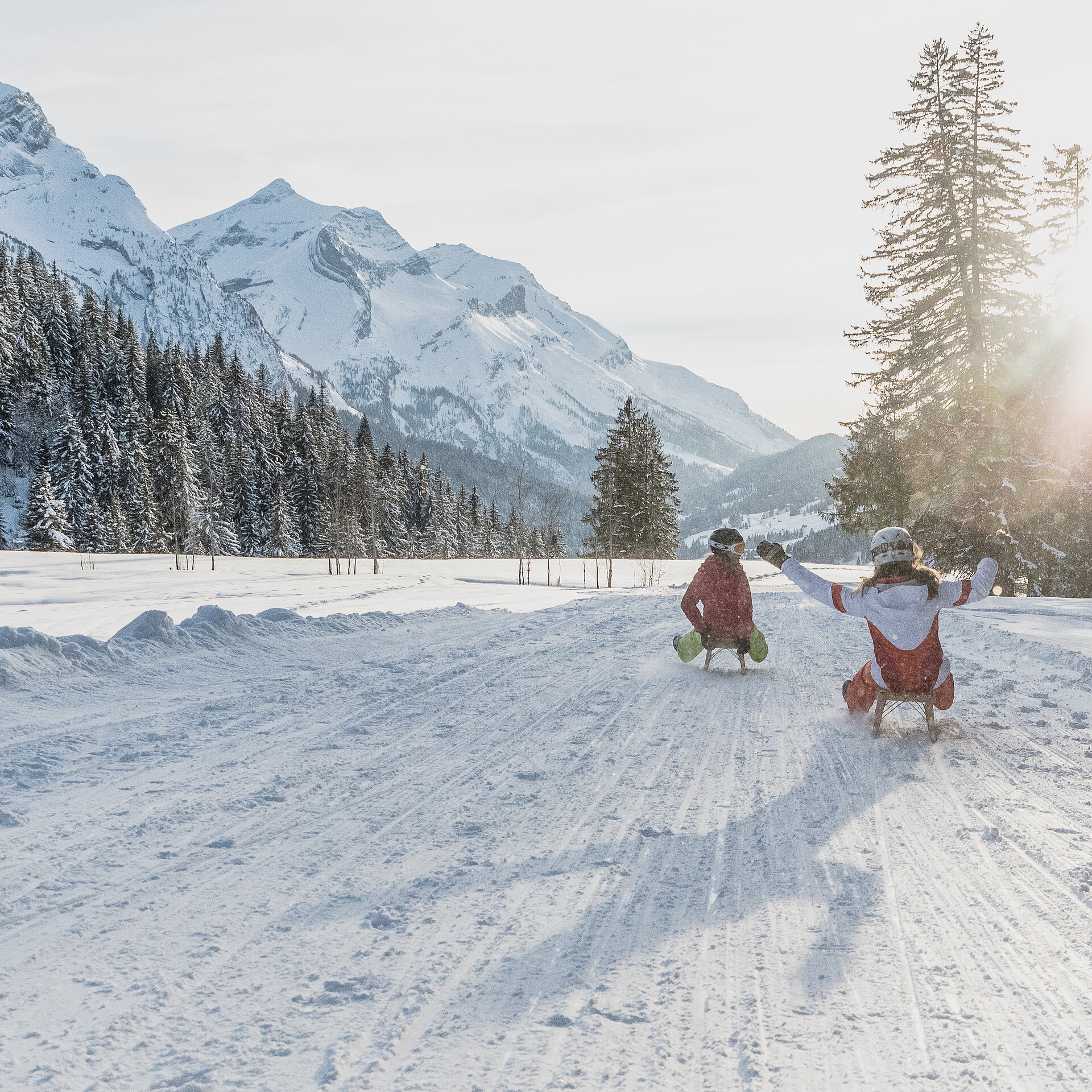 <p>Zwei Personen in Winterkleidung sitzen auf Schlitten inmitten einer verschneiten Winterlandschaft in Gsteig.</p>