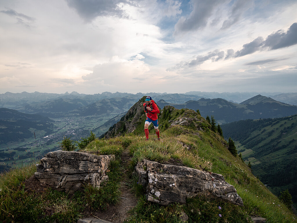 Person in roter Kleidung rennt auf einem Wanderweg den Berg hoch.