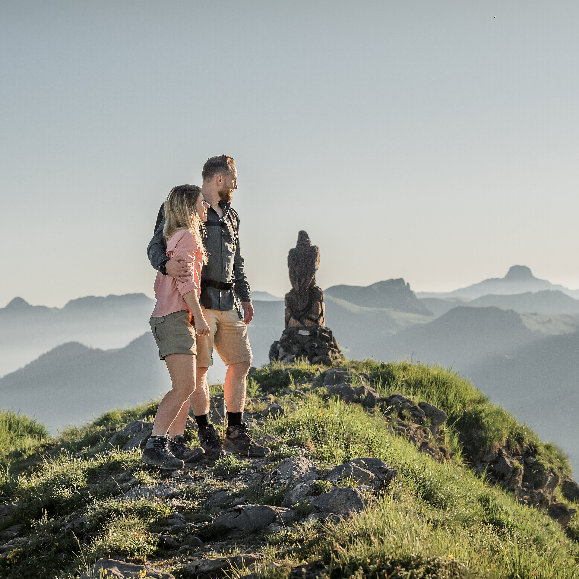 Ein Paar, welches auf dem Rinderberg steht und den Sonnenuntergang betrachtet.
