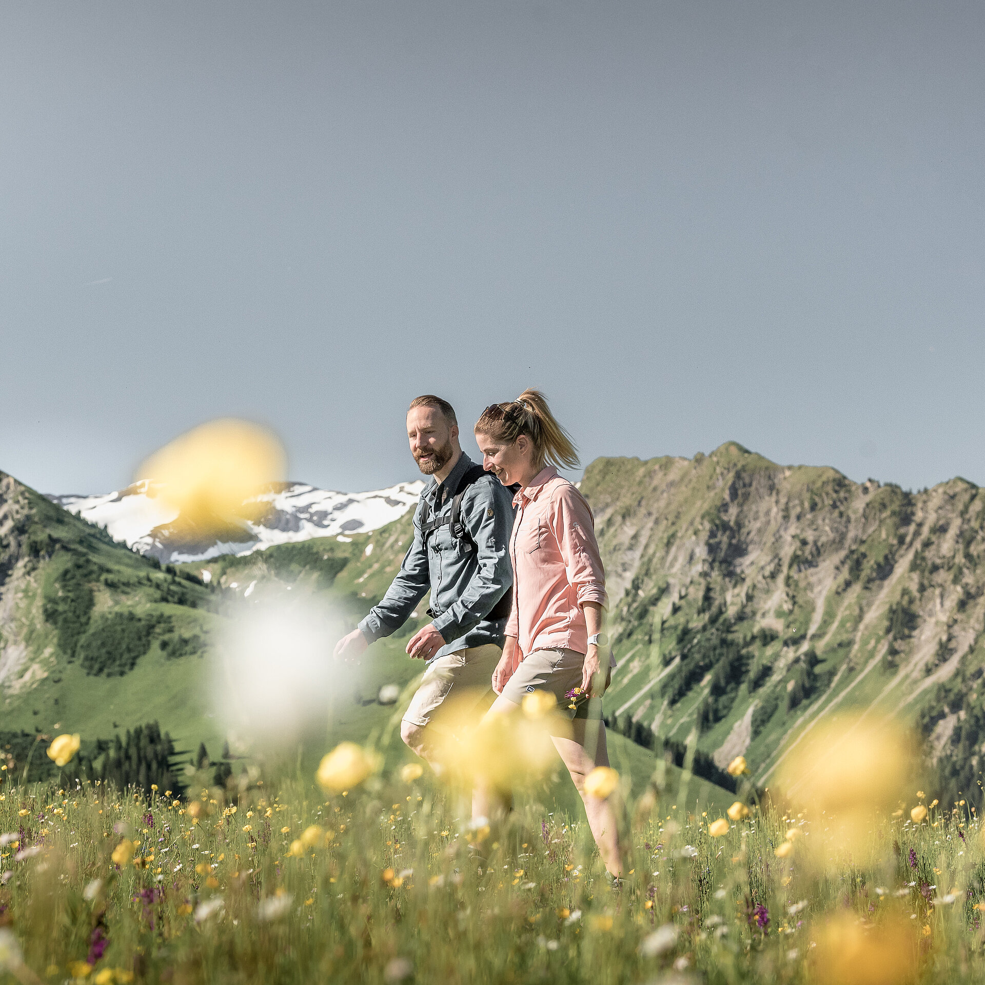 Ein Pärchen läuft zusammen auf einem Wanderweg neben Blumen.&nbsp;