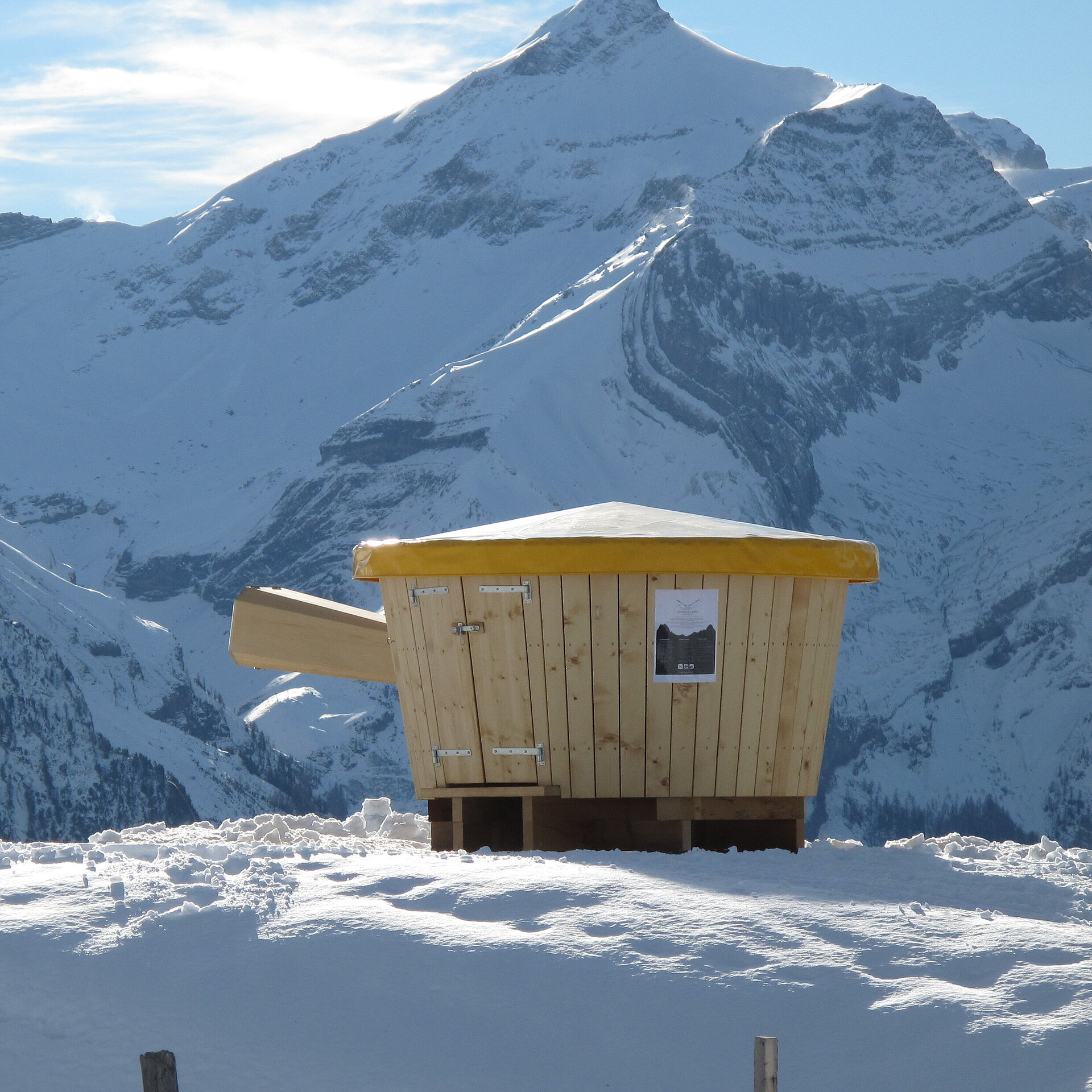 Hölzernes XXL Fondue Caquelon vor verschneitem Bergpanorama.