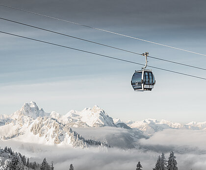 Fokus ist auf der Saanersloch Gondelbahn mit verschneitem Bergpanorama im Hintergrund