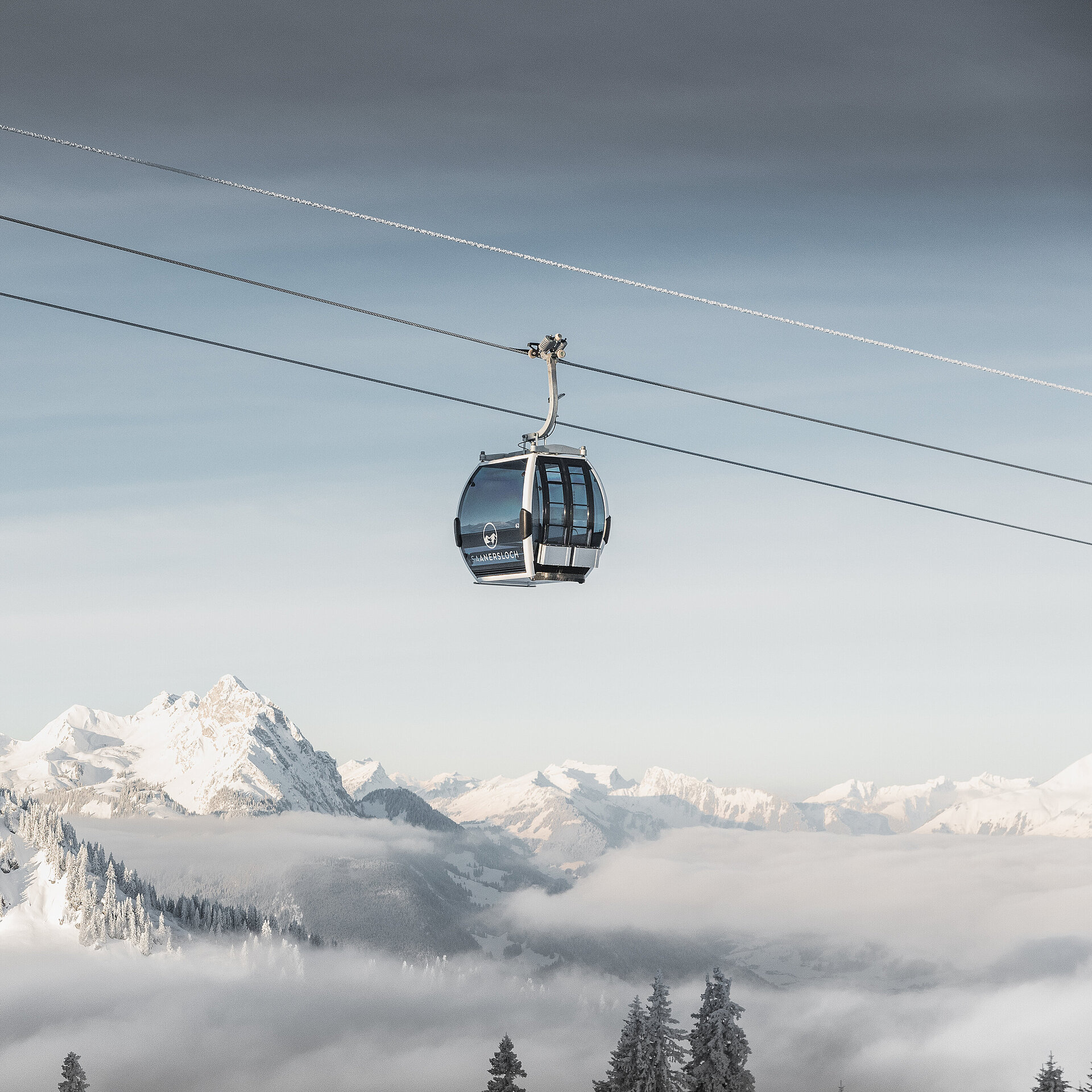 Fokus ist auf der Saanersloch Gondelbahn mit verschneitem Bergpanorama im Hintergrund