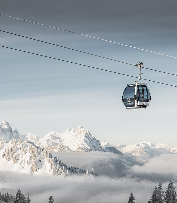 Fokus ist auf der Saanersloch Gondelbahn mit verschneitem Bergpanorama im Hintergrund