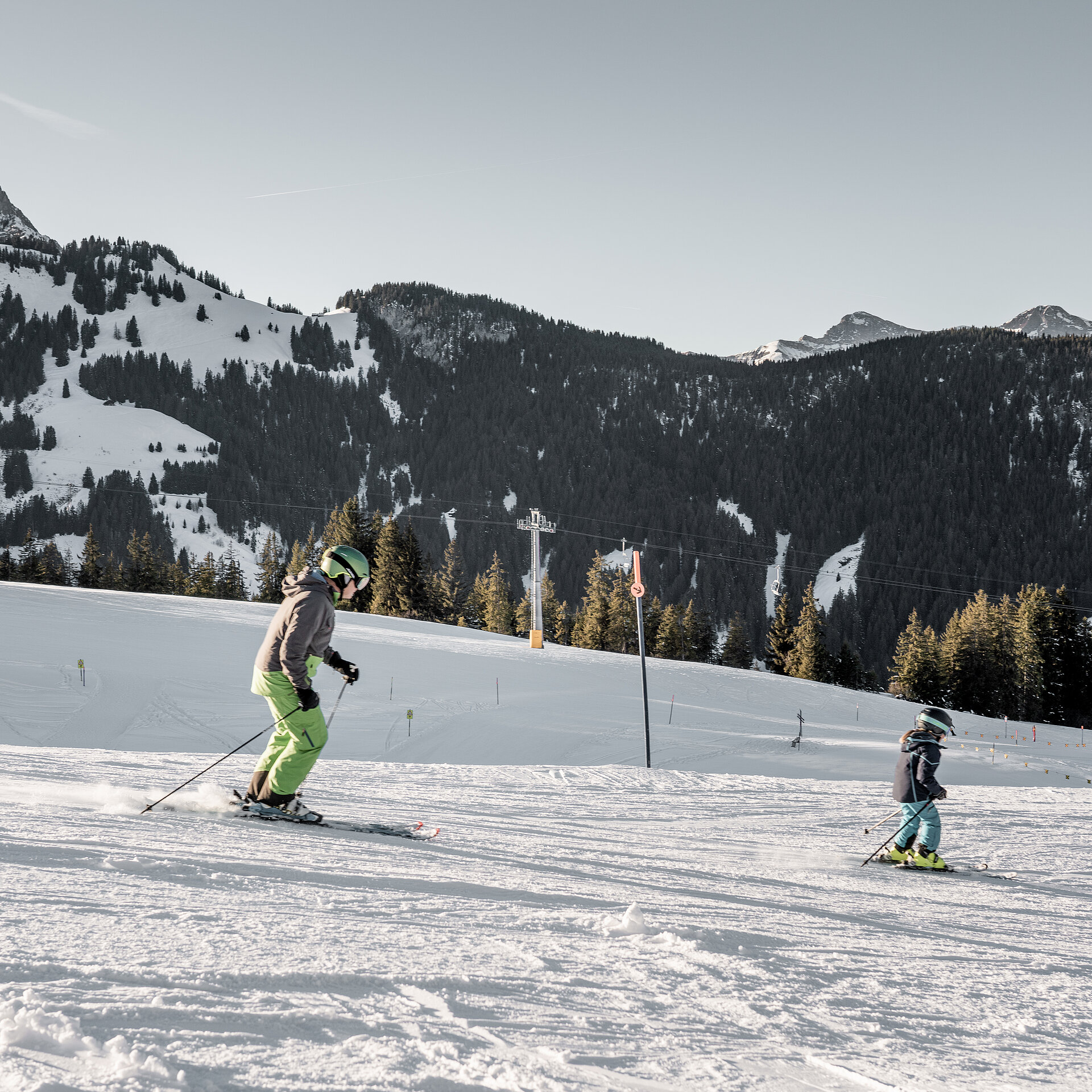 Ein Vater und sein Kind fahren hintereinander auf einer Piste auf dem Eggli Ski.