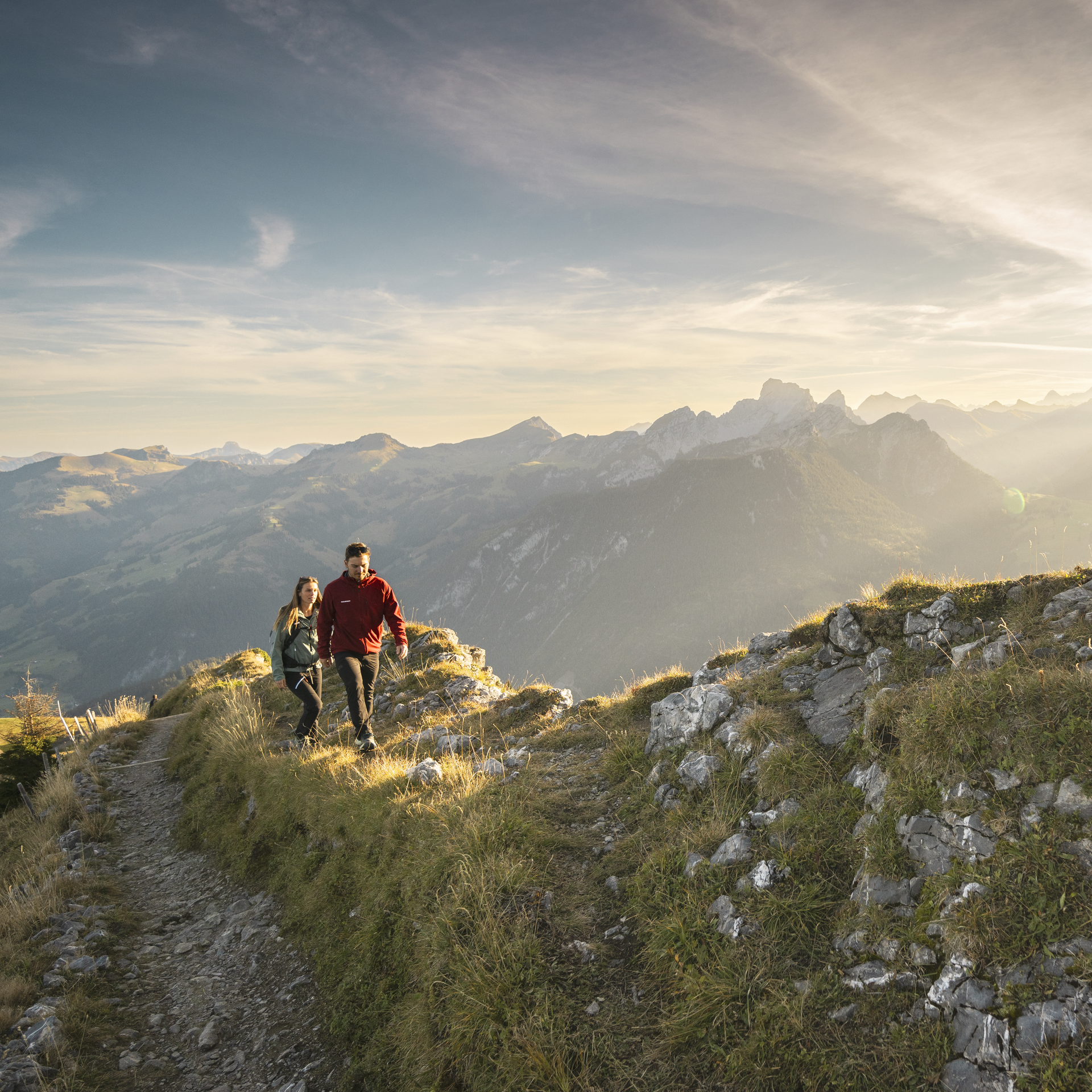 Ein Paar wandert einen wunderschönen Pfad hinauf zum Berggipfel, umgeben vom herbtlichen Bergpanorama.