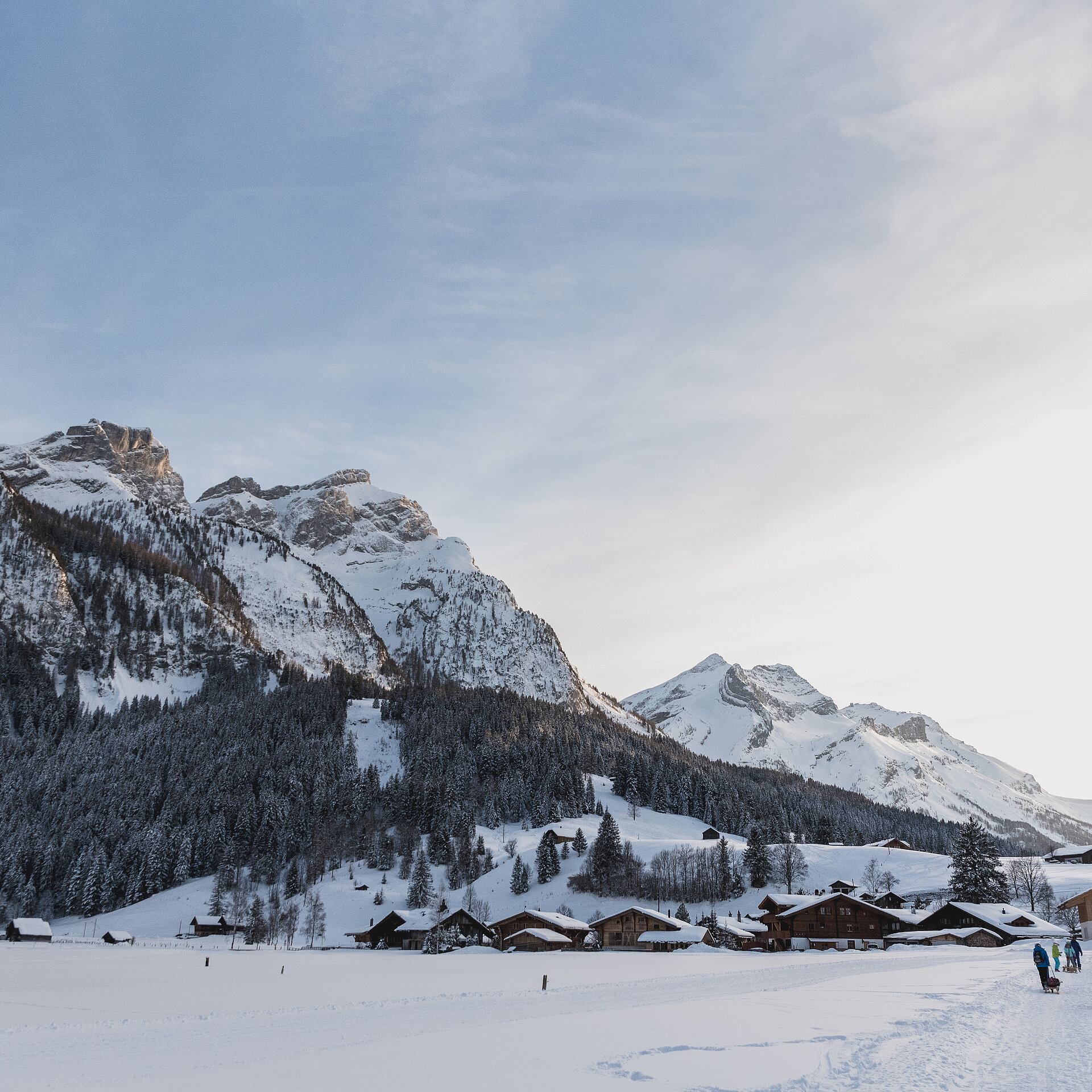 Schneebedeckte Landschaft von Gsteig mit Menschen und Schlitten.