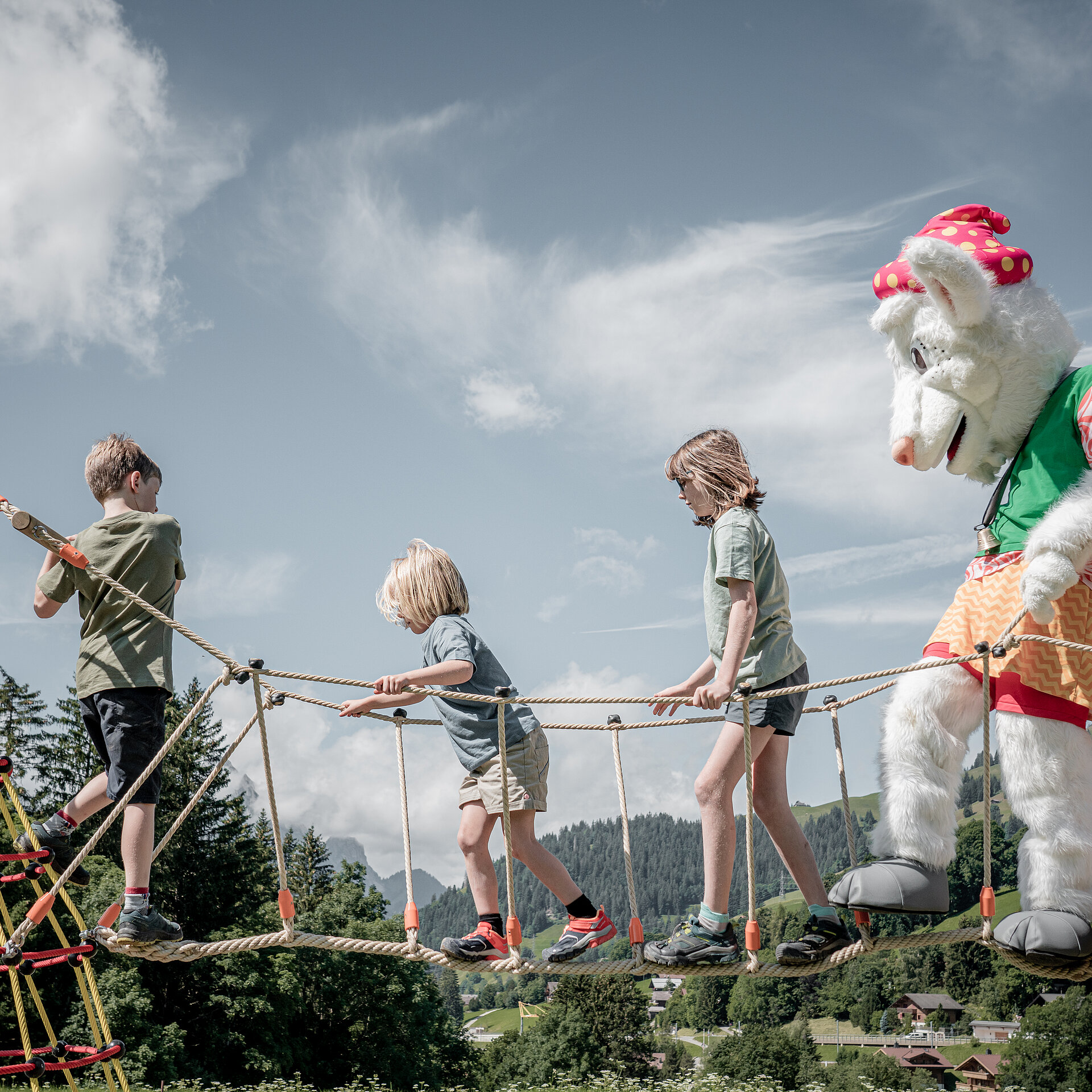 Saani, welche mit Kindern über einen Spielplatzgerät balanciert.