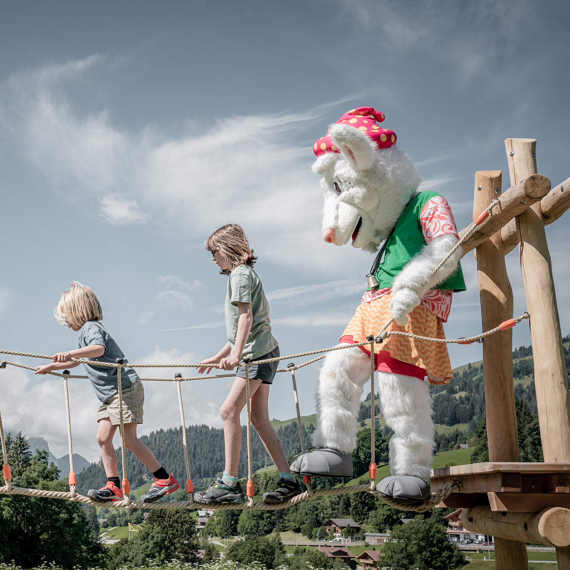 Saani, welche mit Kindern über einen Spielplatzgerät balanciert.