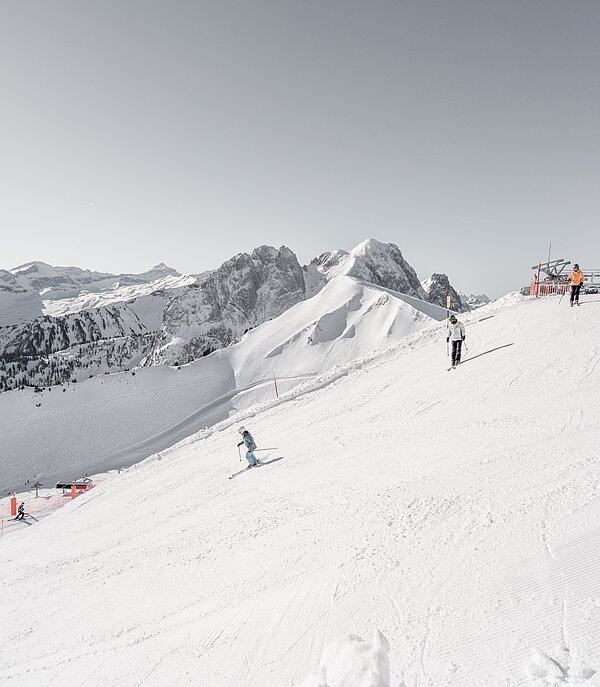 Verschneite Skipiste der La Videmanette mit mehreren Skifahrern vor alpiner Bergkulisse.&nbsp;
